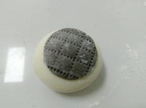 白面团搓圆，然后贴上黑色圆面片。再用干净的梳子，压出印痕，也可以用刀背。