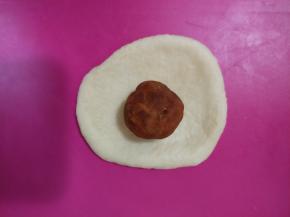 取一块面团擀开，放入樱桃黄金酥馅，再像包包子一样包好，滚圆，收口朝下。