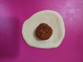取一块面团擀开，放入樱桃黄金酥馅，再像包包子一样包好，滚圆，收口朝下。