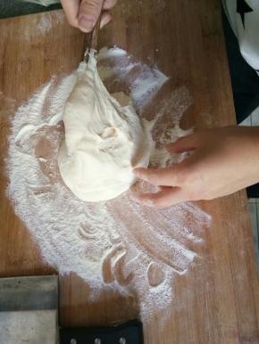 面团用筷子挑到撒满了面粉的面板上。粘上面粉面团就不粘手了