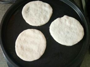 包子褶向下放入电饼铛，按扁成一个饼状。