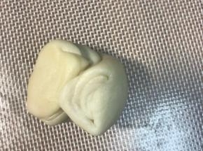 取一个面团，两端像中间对折，按扁