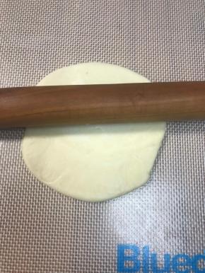 压扁剂子，中间向上一下，中间向下一下，中间向左一下，中间向右一下这样擀，如果大小不够，再来一圈，不要来回擀，面片中间厚外圈薄