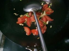 炸茄子的油倒出剩点底油，爆香葱花和一半蒜末，再放入西红柿炒到软