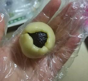 左手大拇指轻压馅料，右手转圈将饼皮慢慢沿馅料周边向上推；