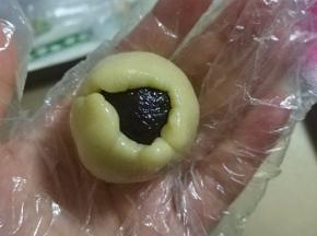 左手大拇指轻压馅料，右手转圈将饼皮慢慢沿馅料周边向上推；