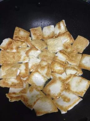 取出平底锅，倒入适量的油，把切好的豆腐放入煎至二面微黄，盛出。