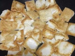 取出平底锅，倒入适量的油，把切好的豆腐放入煎至二面微黄，盛出。