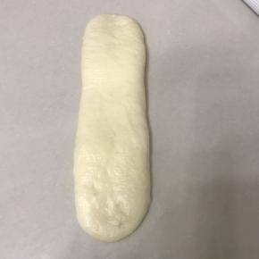 继续擀成长舌型。宽度比吐司盒底部小1.5 公分左右。