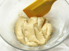 筛入月饼预拌粉。用刮刀翻拌均匀，成为比较有光泽的面团，盖保鲜膜醒发半个小时左右。