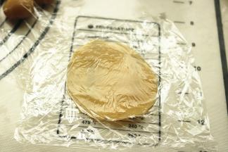 饼皮按扁，用两层保鲜膜包着，擀开成比较薄的片。