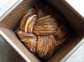 18.编好后，尾部捏紧，两边分别向中间卷，中间漂亮的部分朝上，放在水立方吐司盒中进行发酵。