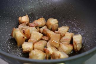 把焯过血沫的肉块放进去，翻炒上色，边炒边用锅铲按压，使五花肉里的油脂逼出去一些；