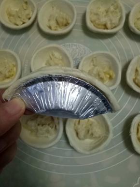 拿起一个挞皮对折，包住榴莲，边缘捏紧