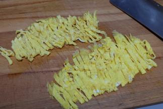 先后摊两张鸡蛋皮出来，对折，切成细条；