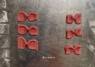 再切出小长方块，中间用筷子夹紧，做成蝴蝶结的样子，粘在红色腰带中间