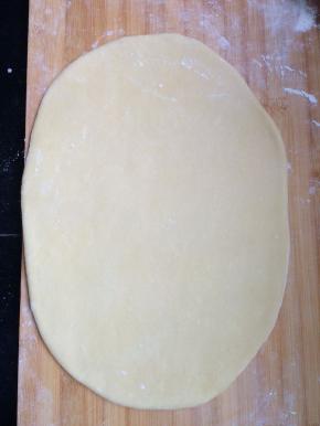 将面板上撒上一层面粉，把揉好的面团，擀成长方形的薄片。