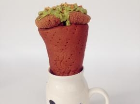 将面包桶放在高身杯中，将切成小粒的芒果放进面包桶底部，将蛋糕放上面。抹茶味巧克力隔水融化，淋在蛋糕上面，花生碎沾在巧克力上