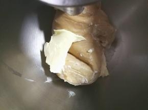 厨师机开至揉面档程序，揉至面团表面光滑，大致出膜加入盐和黄油