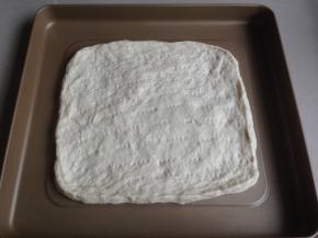 排气后，松驰15分钟，再擀平，放在烤箱自带的不粘烤盘上，松驰15分，用叉子叉出小孔