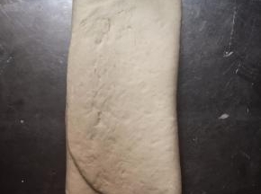 翻面，两边分别向中间三分之一处折起来，然后案板上再撒上些许干粉，擀开