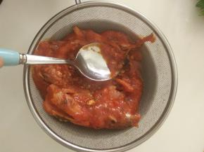 把一罐沙丁鱼倒在筛网上，过滤去汤汁，并用勺子把鱼肉压碎。