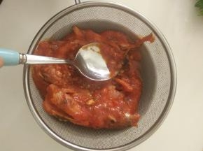 把一罐沙丁鱼倒在筛网上，过滤去汤汁，并用勺子把鱼肉压碎。