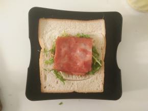 放上适量苦菊菜和一片煎熟的培根。