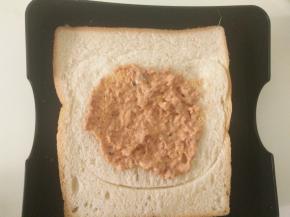 取一片土司，抹上沙丁鱼酱。