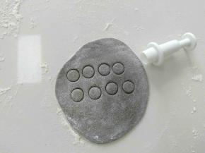 取部分白面团，加入适量可可粉，揉匀，如图，压出黑色圆面片，做眼睛。