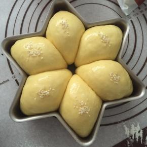 取出烤盘，面包刷上一层薄薄的蛋黄液，放上白芝麻装饰。