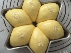 取出烤盘，面包刷上一层薄薄的蛋黄液，放上白芝麻装饰。