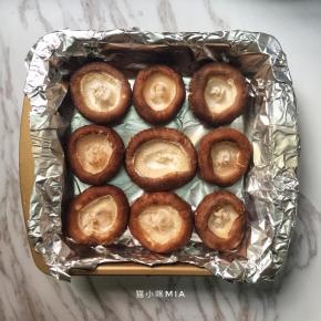准备一个烤盘，并铺上一层锡纸，用手挤出香菇的水分，码放在烤盘上，均匀地撒上一点盐，烤箱180度预热