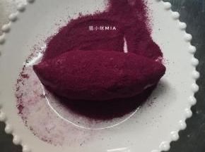 准备一个盘子，倒入紫薯粉，把紫薯面包放盘子里滚一圈，让面包表面沾满紫薯粉