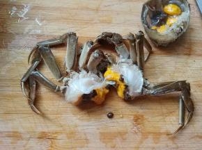 拿下蟹盖后，摘掉蟹心蟹胃，把蟹从中间分开。