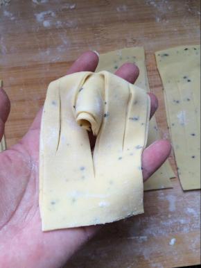 将划好的面片拿起来，丛一端往中间划得长的中间折过去