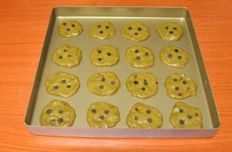 5、用小勺舀起面糊，放在不沾烤盘上，用勺背压平，上面洒几颗巧克力豆