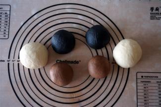 取其中一份156克的面团，加入可可粉揉匀，然后分成两等份。同理，另一份156克的面团加入竹炭粉揉匀后分成两等份。给面团盖上保鲜膜，松弛30分钟。