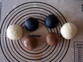 取其中一份156克的面团，加入可可粉揉匀，然后分成两等份。同理，另一份156克的面团加入竹炭粉揉匀后分成两等份。给面团盖上保鲜膜，松弛30分钟。