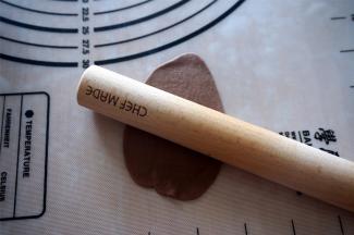 取一个可可小面团，擀成椭圆形面片，沿着长边卷起来，然后用手搓至比吐司盒稍微短一些。