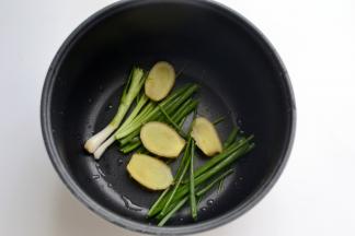 取适量的香葱段和姜片铺在电饭煲底部