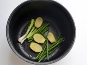 取适量的香葱段和姜片铺在电饭煲底部