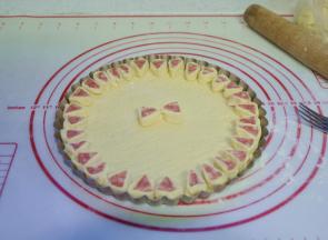 6、将火腿肠段底部沾些清水，然后黏在披萨饼胚上，围成一圈；