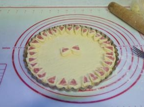 6、将火腿肠段底部沾些清水，然后黏在披萨饼胚上，围成一圈；