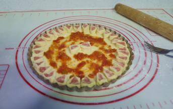 7、用叉子在披萨饼胚底部扎小孔，刷上自制披萨酱；