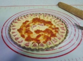 7、用叉子在披萨饼胚底部扎小孔，刷上自制披萨酱；