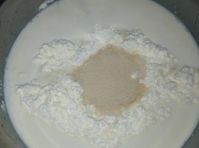 牛奶倒入面粉中，倒入酵母粉。新手可以先将酵母粉倒入牛奶中溶解，再倒入面粉中。