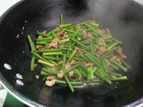 倒入蒜苔翻炒均匀后加入少量清水，加盖焖煮一会，开盖续炒至蒜苔快熟。