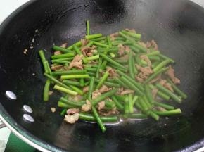 倒入蒜苔翻炒均匀后加入少量清水，加盖焖煮一会，开盖续炒至蒜苔快熟。
