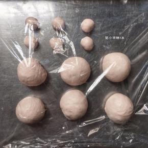 将发酵好的面团先分出一份30克的面团，将用来做小猫咪的耳朵，剩余的面团平均分成15份，都揉圆用保鲜膜盖好醒发10分钟，醒发完后，15份揉圆的面团放烤盘，30克的面团平均分成30份做成耳朵的样子
（我这里只做了6个迷你汉堡，其它的就做成正常尺寸的小餐包了）